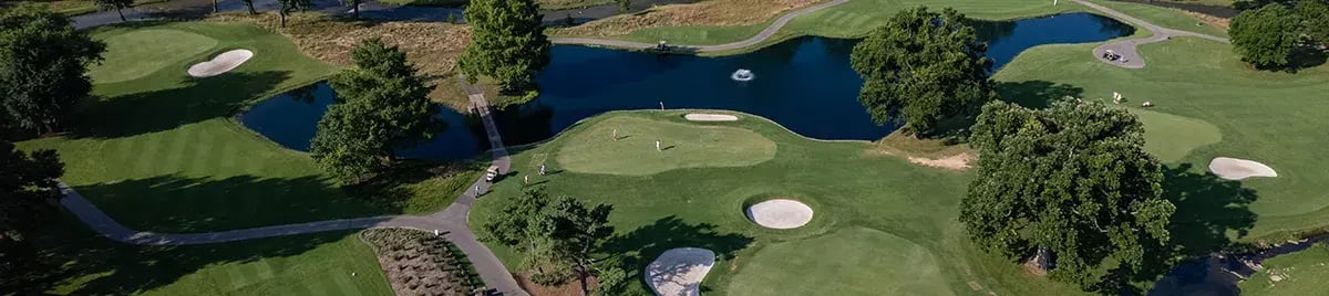 drone shot of golf course with carts water trees