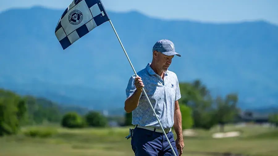 male golfer holding flag with TGA printed on it
