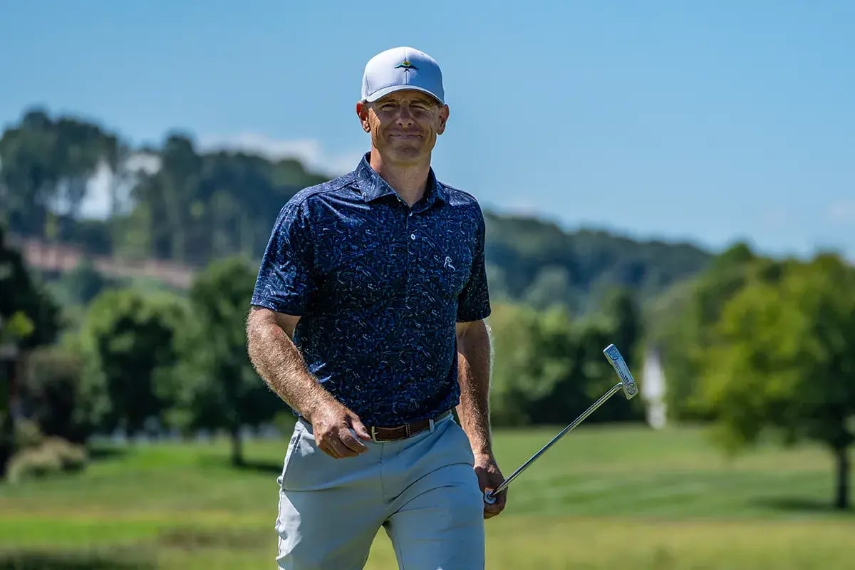 man walks carrying golf club