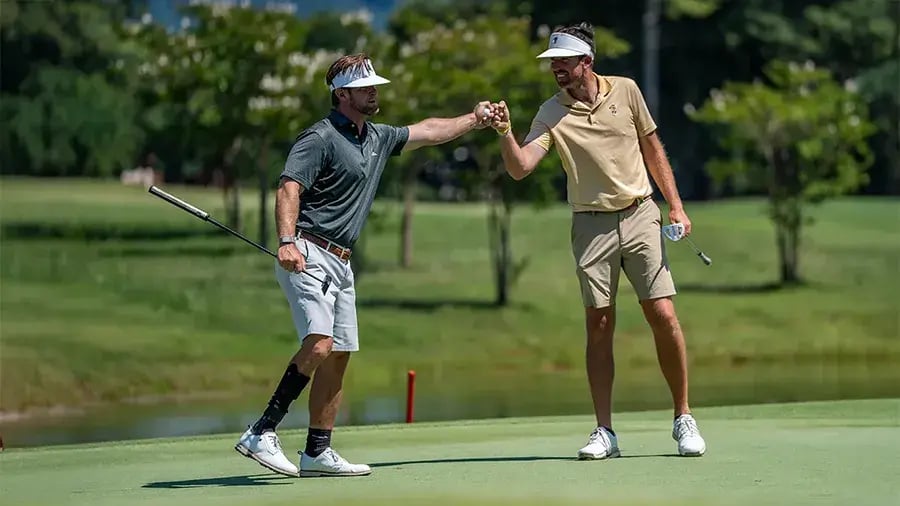 two male golfers fist bump lower leg amputee