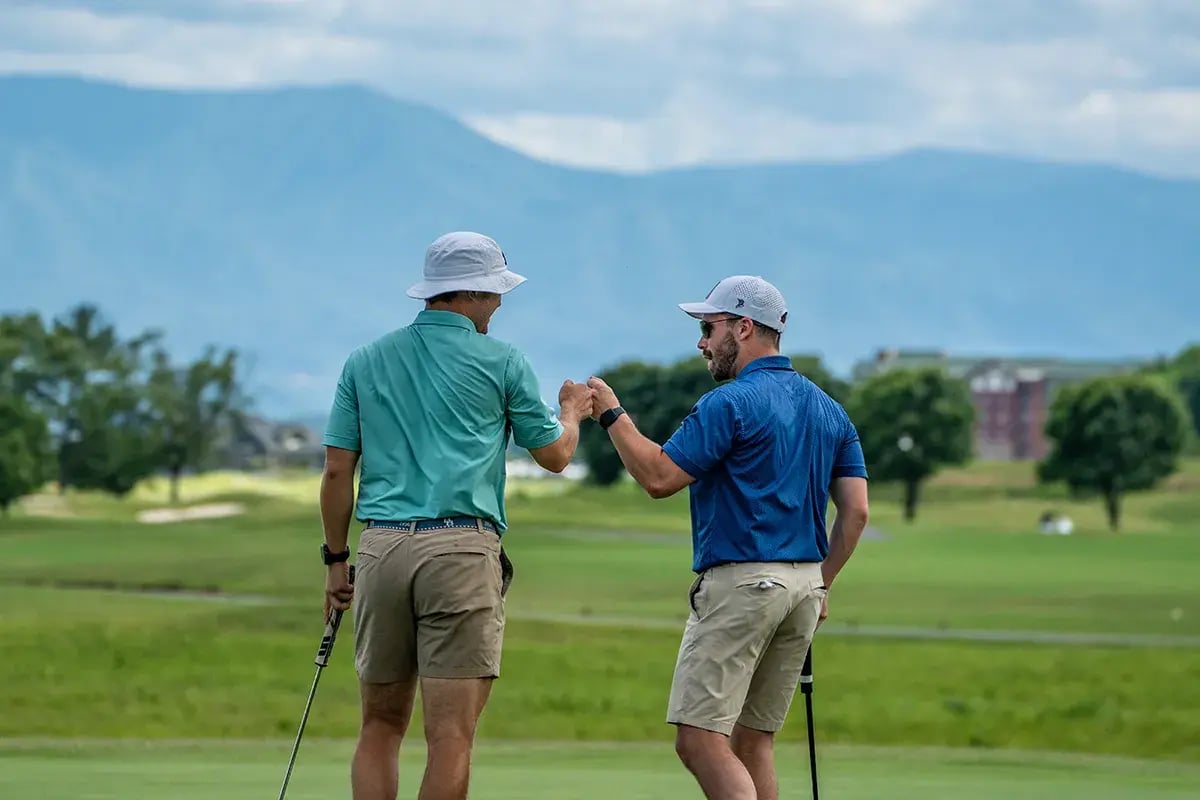 two male golfers fist bump