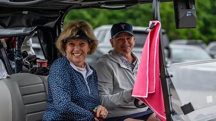 two women golfers in cart smiling
