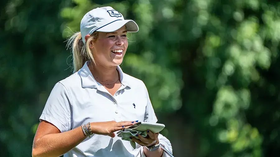 young female golfer taking off gloves smiling