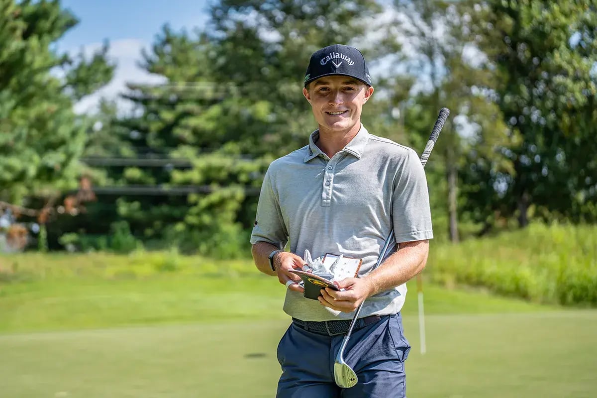 young male golfer taking off gloves