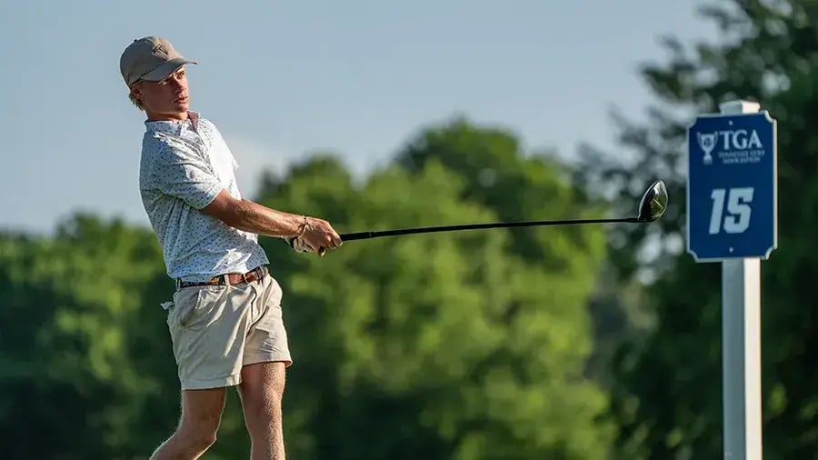 young male golfer watching ball post swing