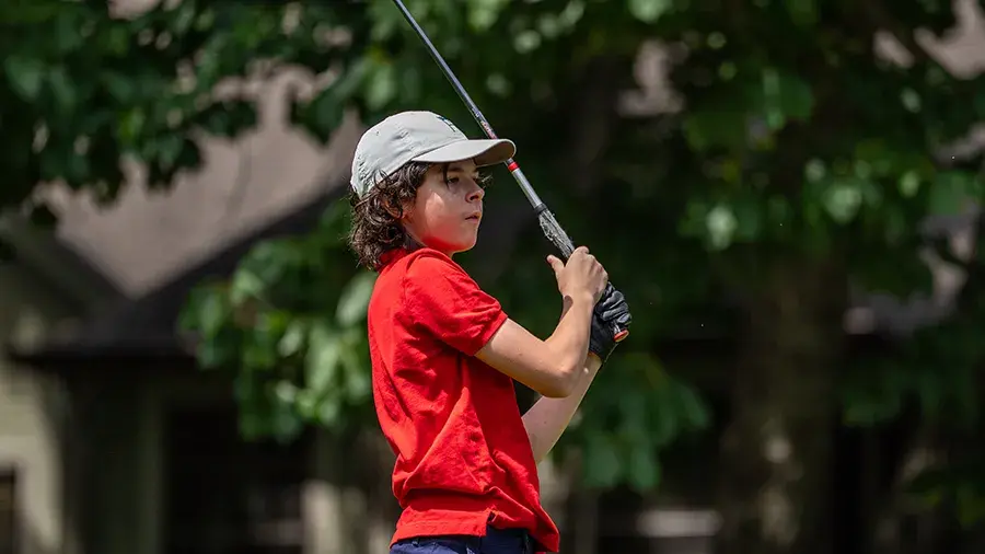 male youth stands watching ball post swing