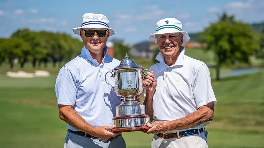 two male golfers standing holding trophy